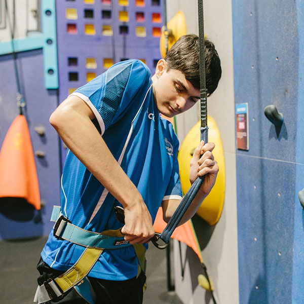 Allied Health Assistant assisting with physiotherapy during a rock-climbing session at Revolution North Lakes, promoting physical skills development.